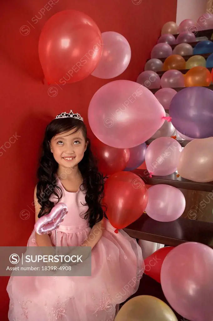Girl Holding Wand Sitting On Stairs With Balloons