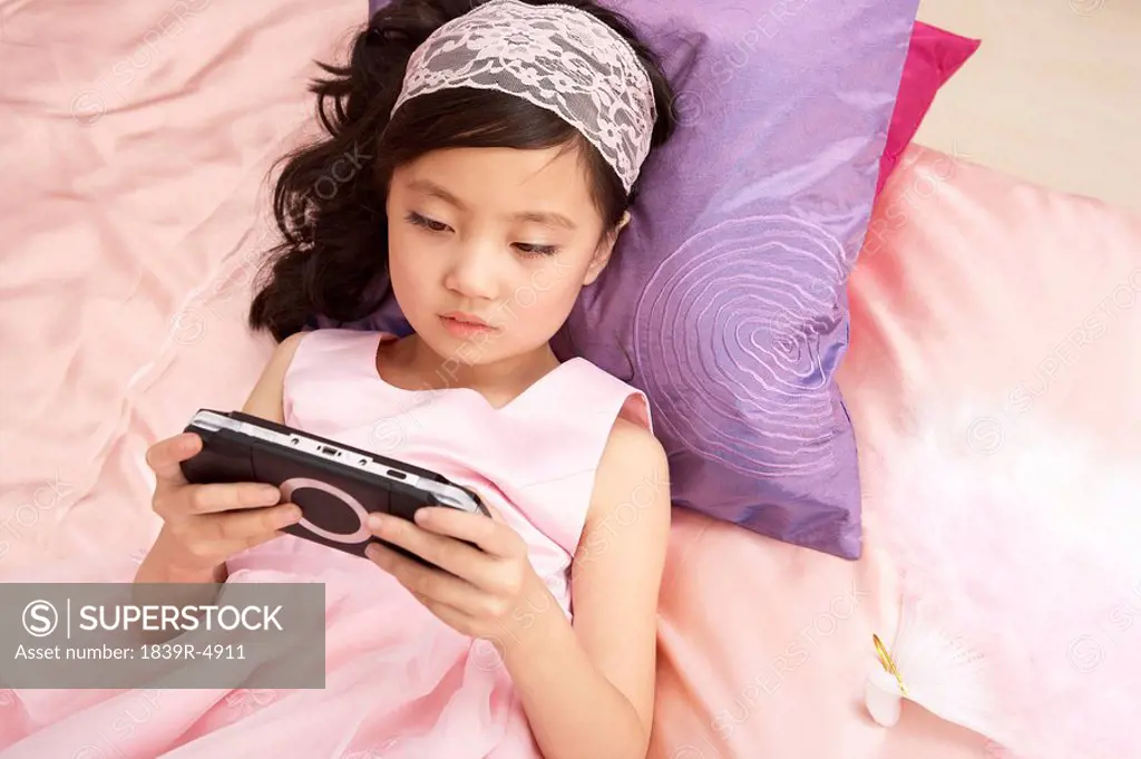 Girl Lying On Bed Playing On Game Console