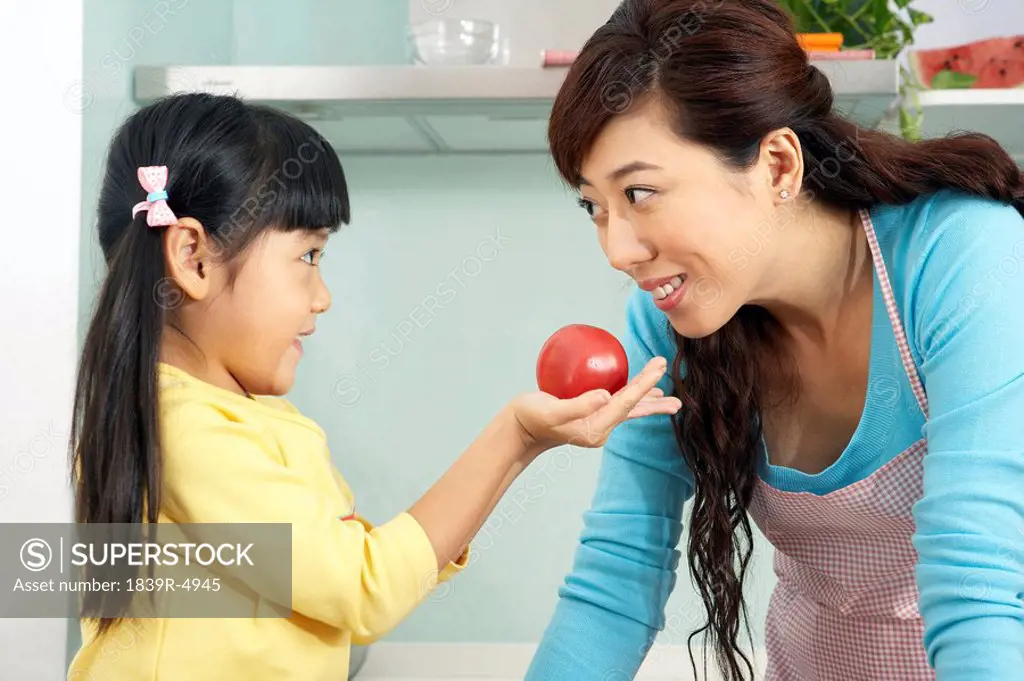 Girl Giving Mother A Tomato