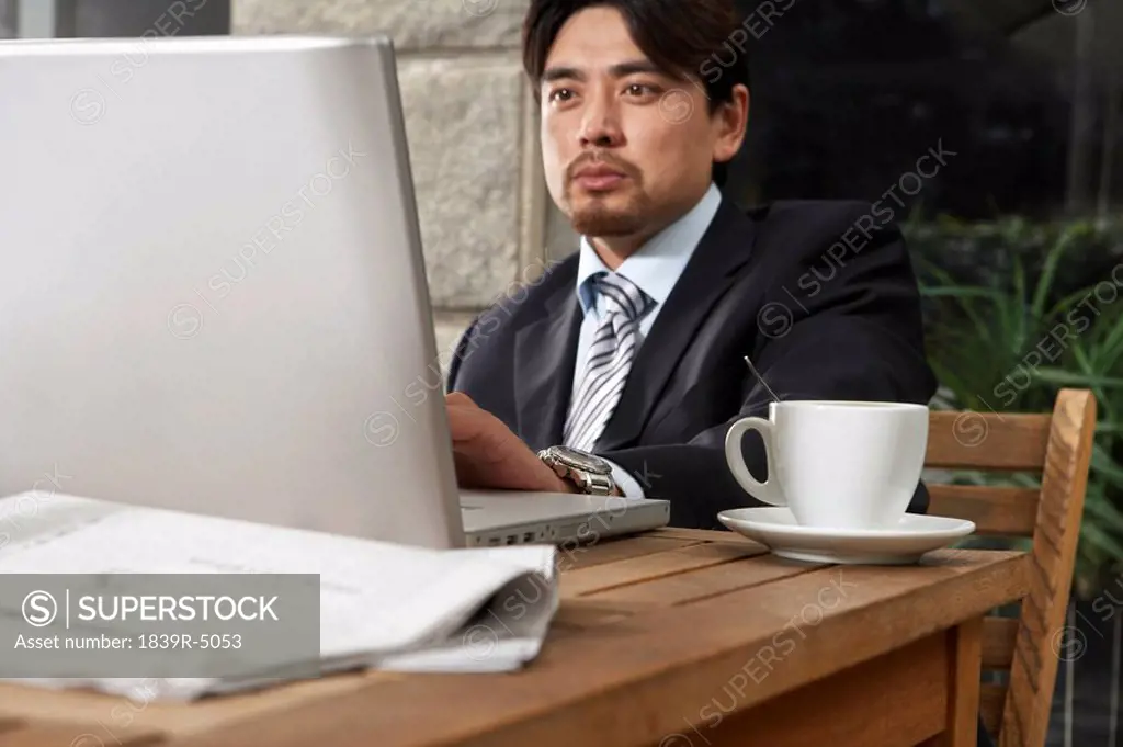 Businessman Using Laptop At Cafe