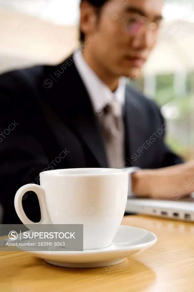 Businessman Using Laptop At Cafe