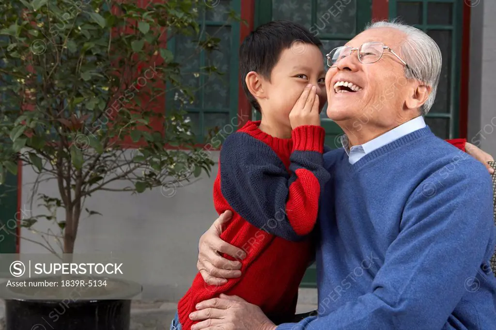 Young Boy Whispering Into Grandfather´ Ear