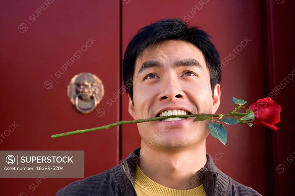 Young Man Waiting Outside Front Door Holding A Rose In His Mouth