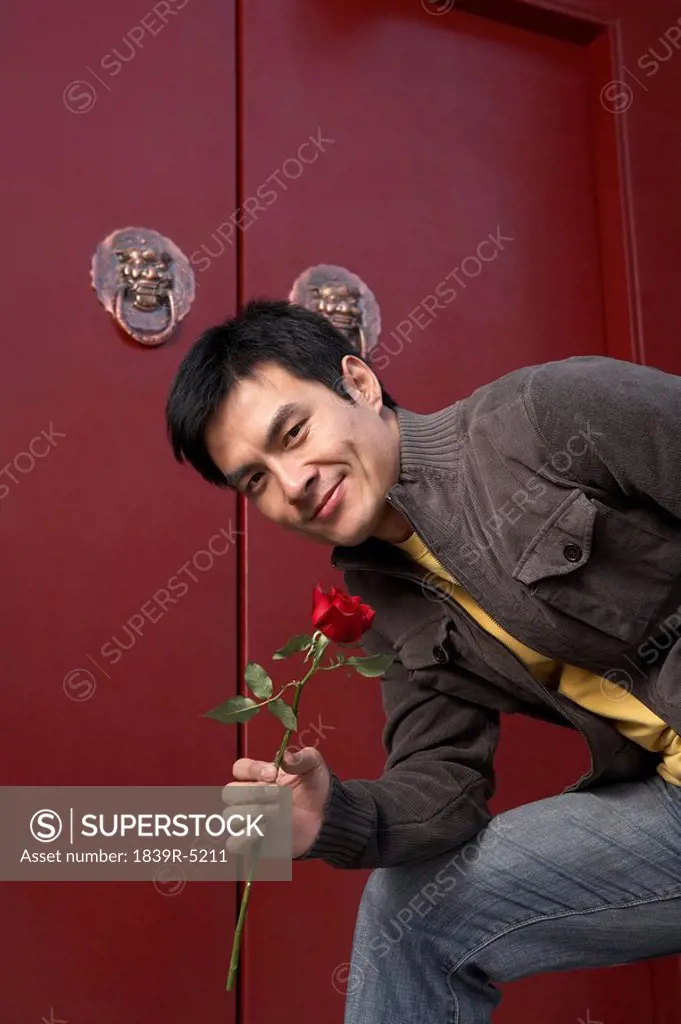 Young Man Waiting Front Door Clasping A Red Rose