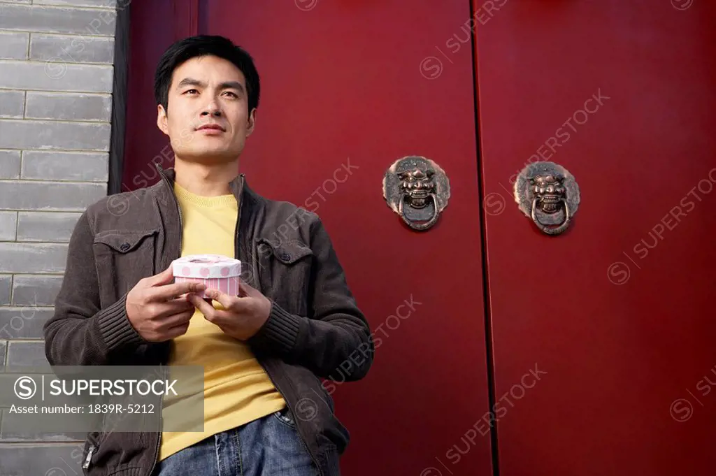 Young Man Waiting Outside Front Door With A Box Of Chocolates