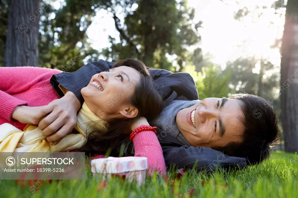 Couple Lying On Grass Looking At Sky