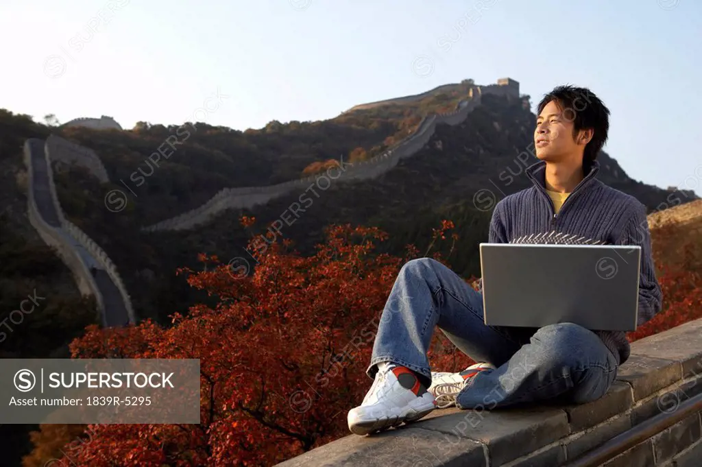Young Man Uses Laptop On The Great Wall Of China