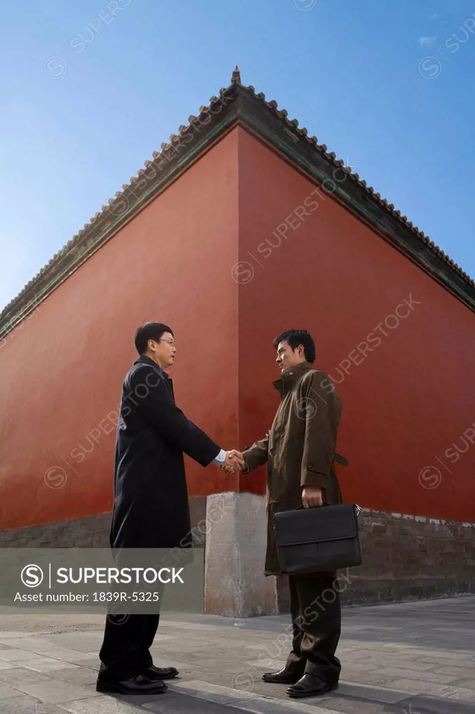 Businessmen Shaking Hands Standing Next To Architectural Structure,