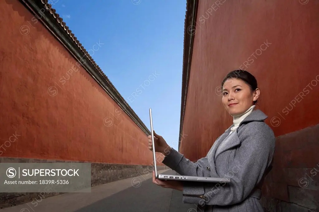 Woman Standing Next To Building Holding Laptop