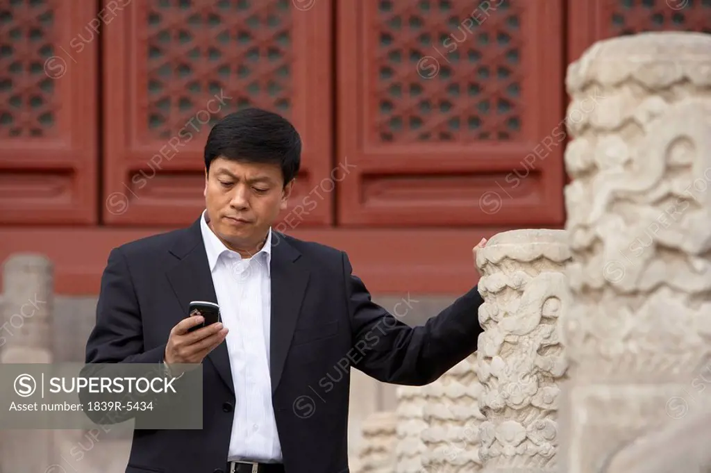 Businessman Using Cellphone In The Forbidden City In Beijing