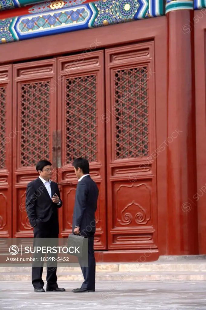 Two Businessmen Talking In The Doorway Of The Forbidden City In Beijing