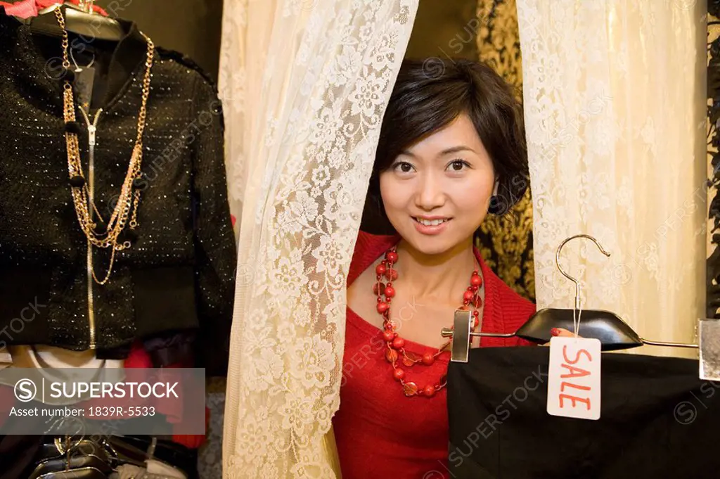 Young Woman Looking At Clothes In Shop Store