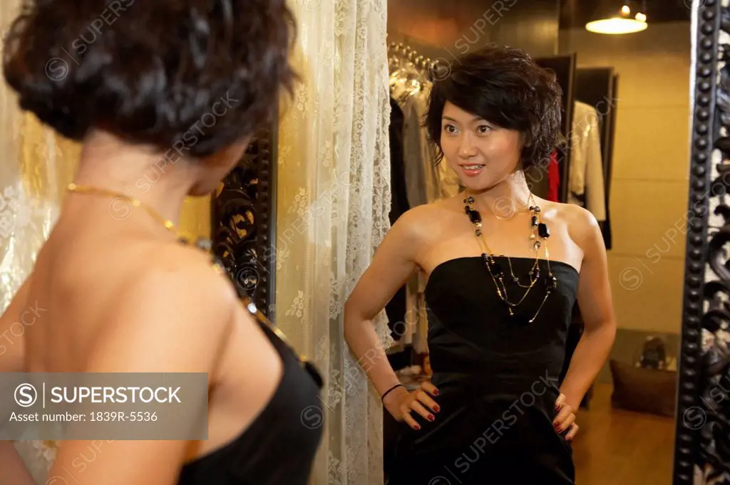Young Woman Trying On Dress And Looking In Mirror
