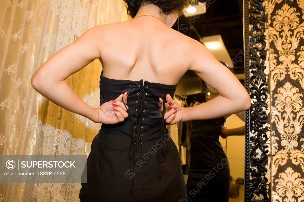 Young Woman Trying On Dress And Looking In Mirror