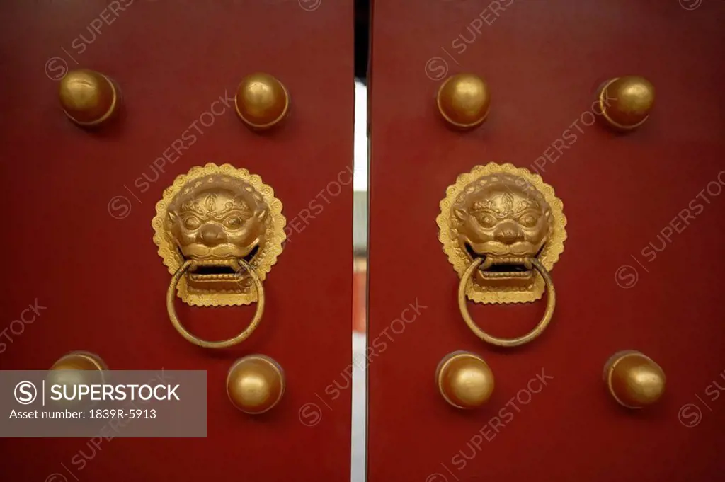Gold Metal Door Knockers On A Red Door