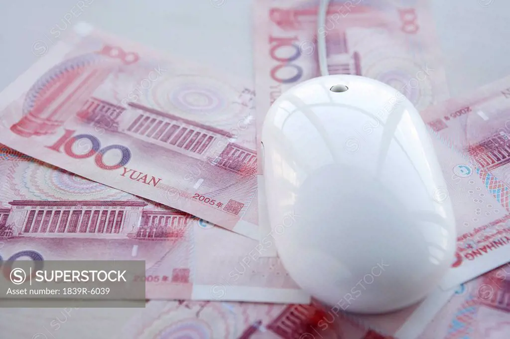 A computer mouse sitting on 100 Yuan notes