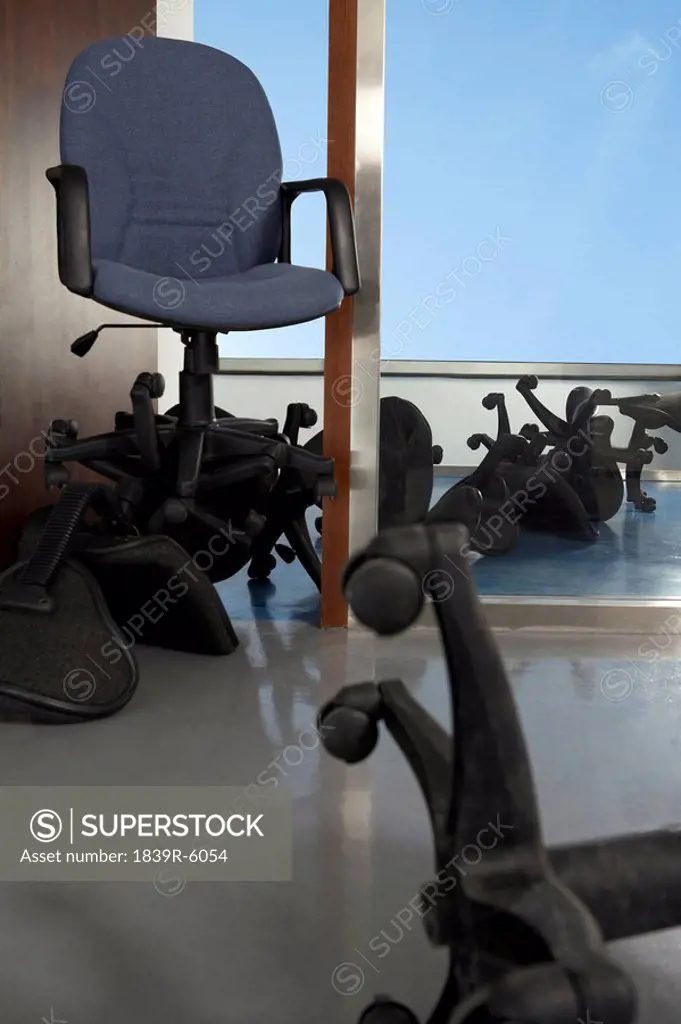 A grey office chair on top of fallen office chairs