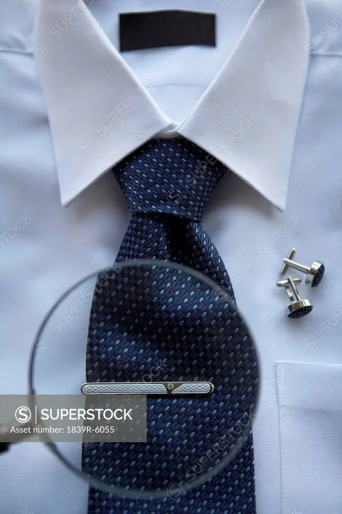 A Magnifying glass focused on a tie clip on a neck tie