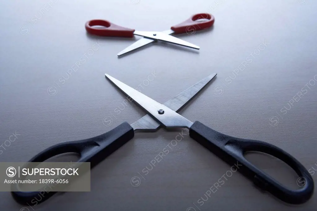 Two pairs of scissors open and facing each other