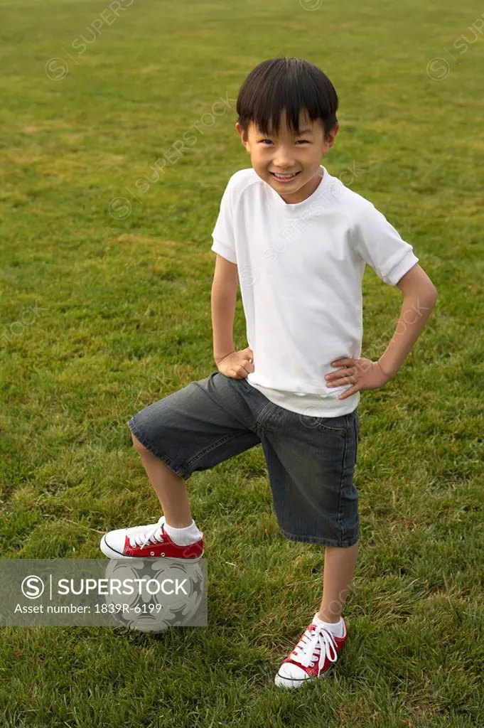 Boy Triumphantly Standing On Soccer Ball