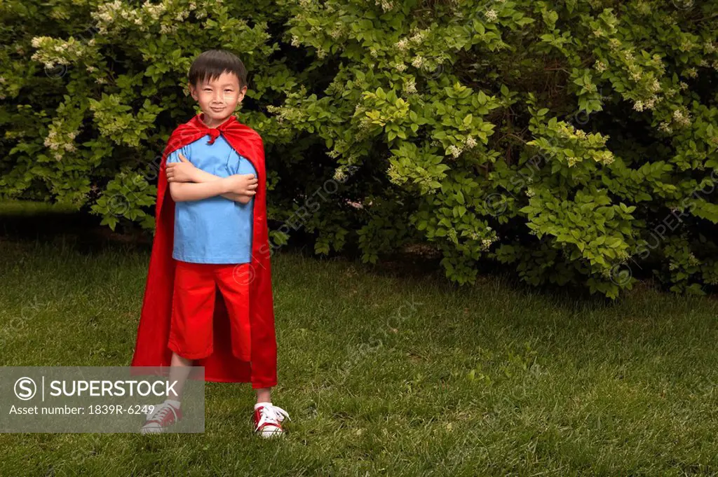 Boy In Red Cape Playing In Garden