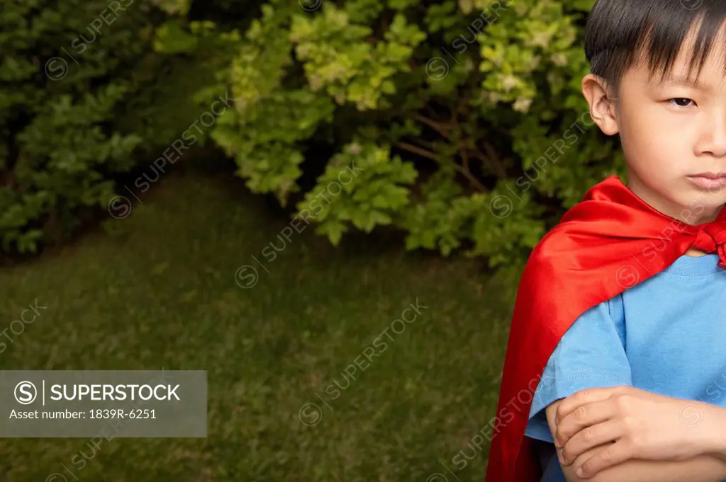 Boy In Red Cape Playing In Garden