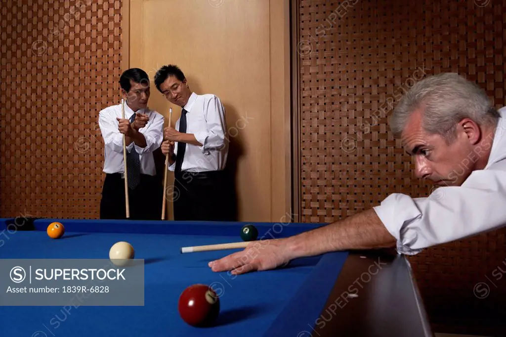 Three professionals play billiards