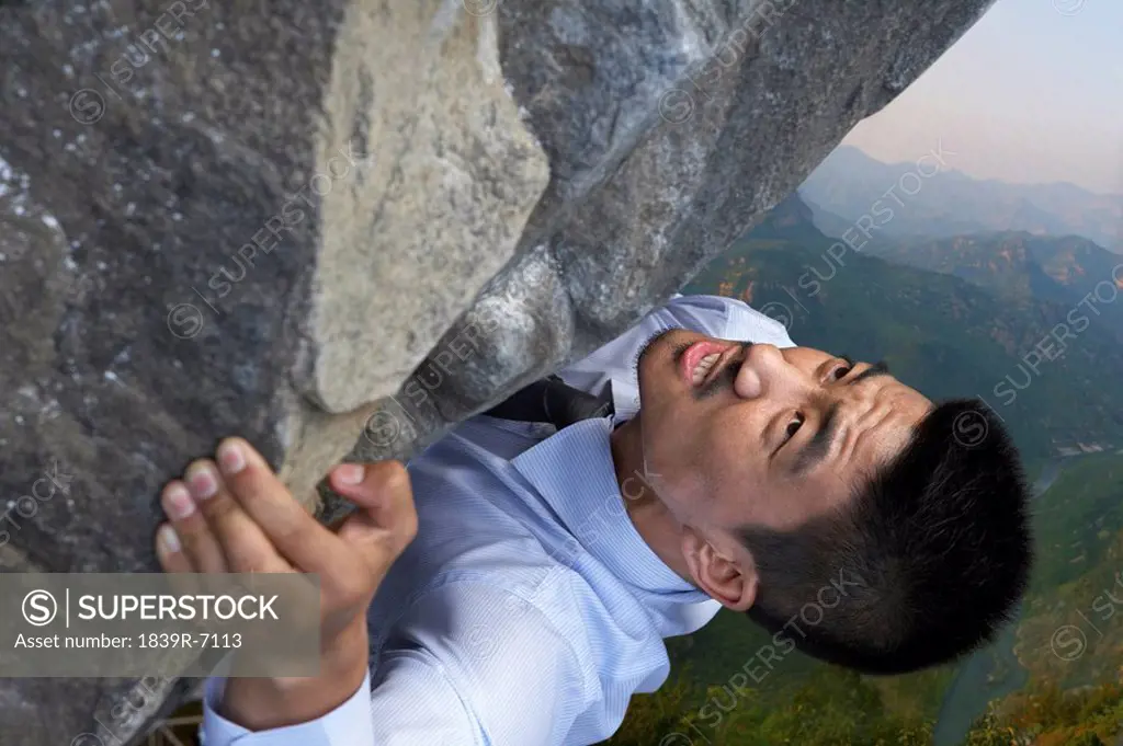 A businessman climbing a rock face