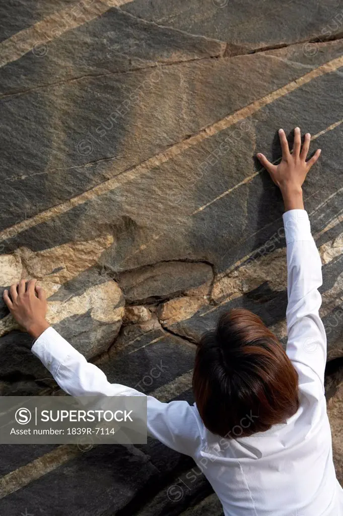A businesswoman climbing a rock face
