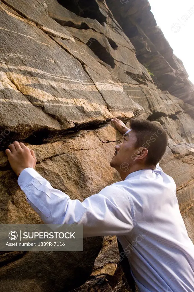 A businessman climbing a rock face