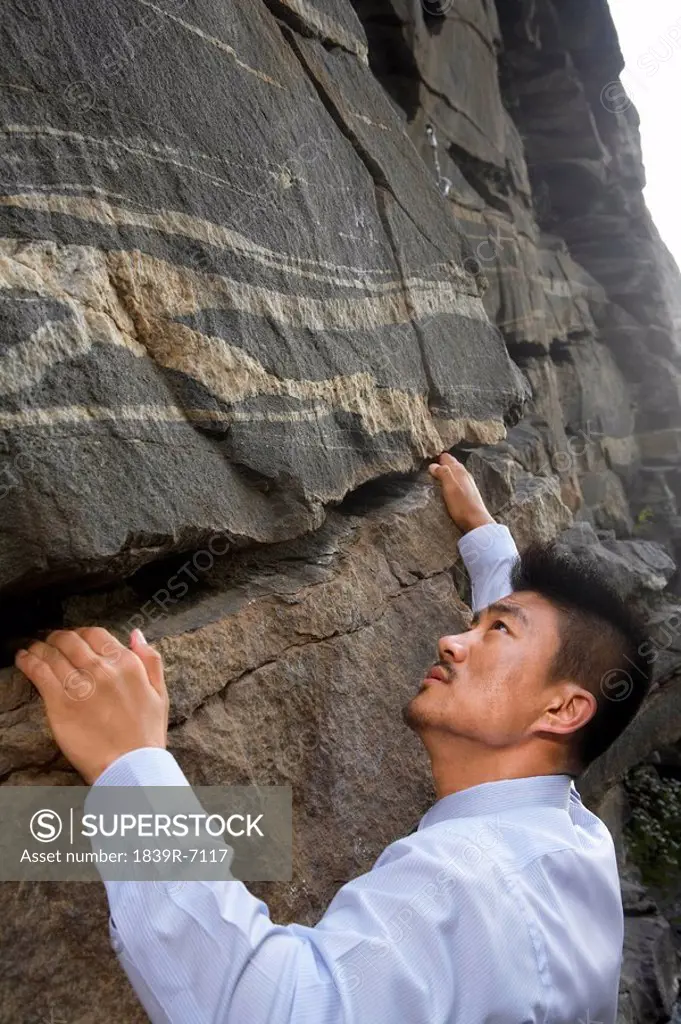 A businessman climbing a rock face