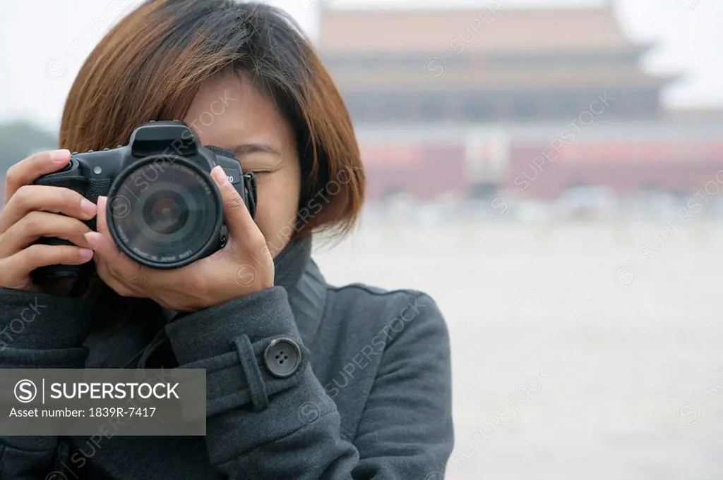Young woman taking a photo in front of Tiananmen Square, Beijing, China