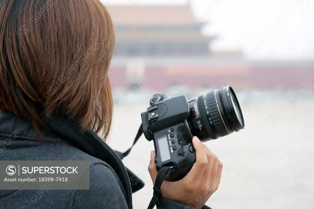 Young woman holding camera looks out at Tiananmen Square, Beijing, China