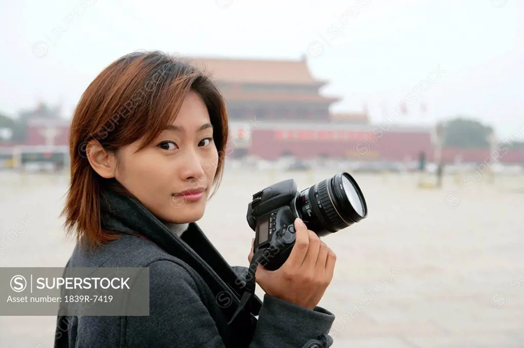 Portrait of a young woman holding camera, Tiananmen Square, Beijing, China