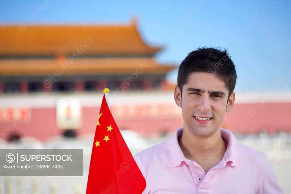 Young man holding a flag in front of Tiananmen Gate, Beijing, China