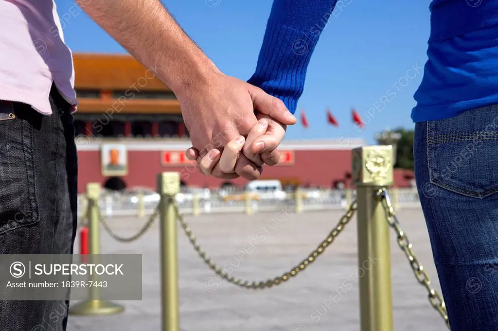 Young couple hold hands in front of Tiananmen Gate, Beijing, China