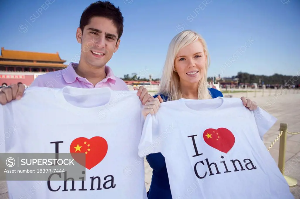 Young couple hold I Heart China t_shirts in front of Tiananmen Gate, Beijing, China