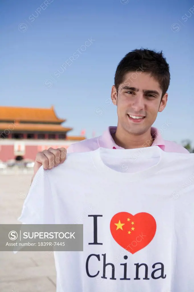 Young man holds an I Heart China t_shirt in front of Tiananmen Gate, Beijing, China