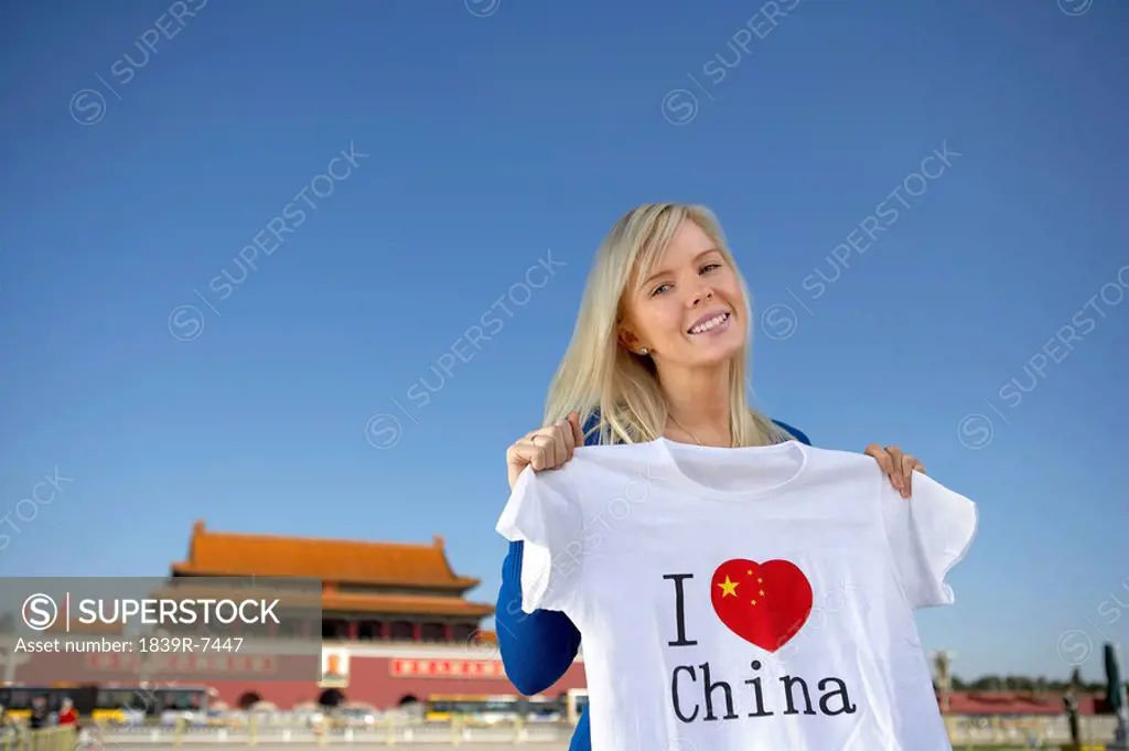 Young woman holds an I Heart China t_shirt in front of Tiananmen Gate, Beijing, China