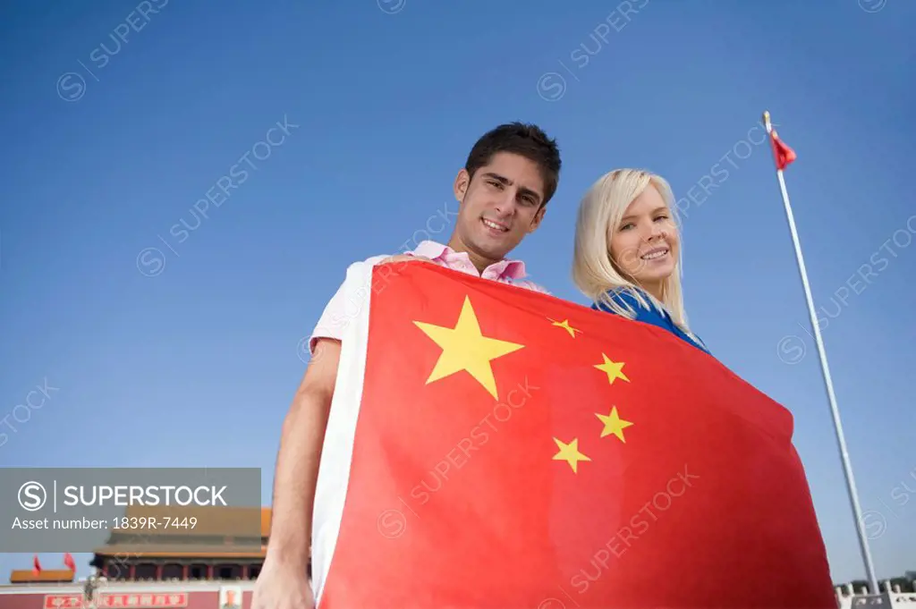Young couple holding a flag in front of Tiananmen Gate, Beijing, China