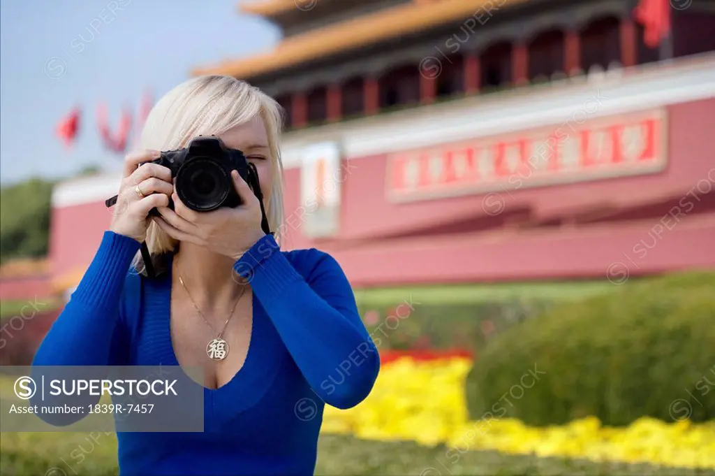 Young woman taking a photo in front of Tiananmen Gate, Beijing, China