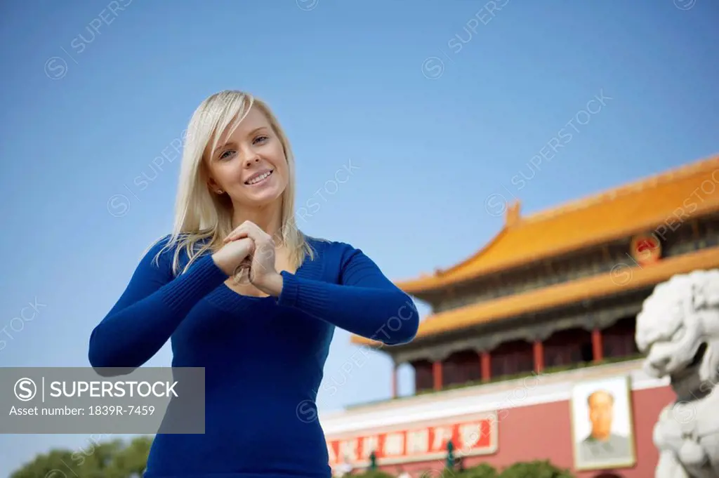 Young woman makes a welcoming gesture in front of Tiananmen Gate, Beijing, China