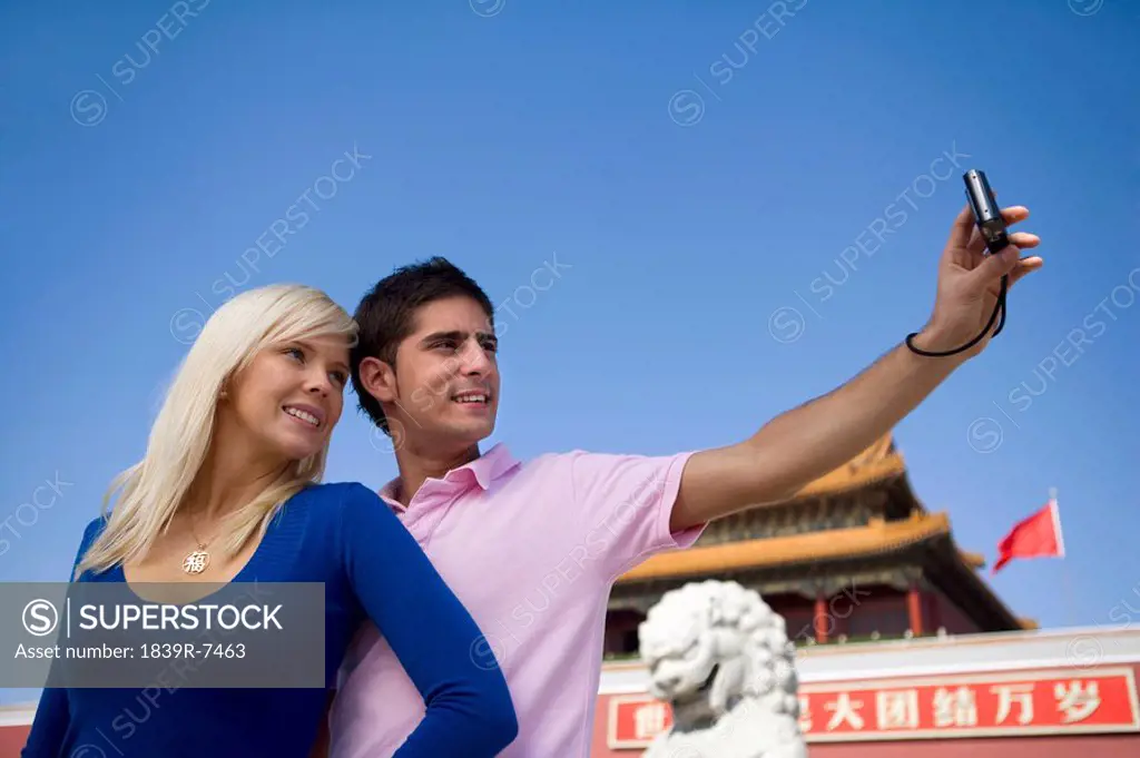 Young couple takes their own picture in front of Tiananmen Gate, Beijing, China