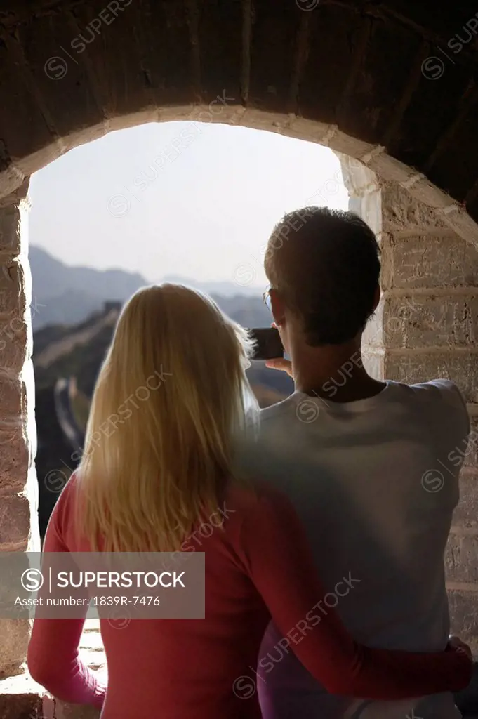 Young couple taking a picture out of a guard tower window at the Great Wall of China