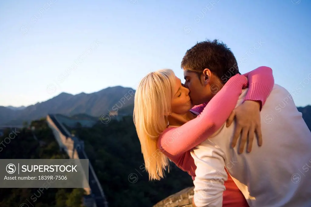 Young couple kiss at sunset at the Great Wall of China