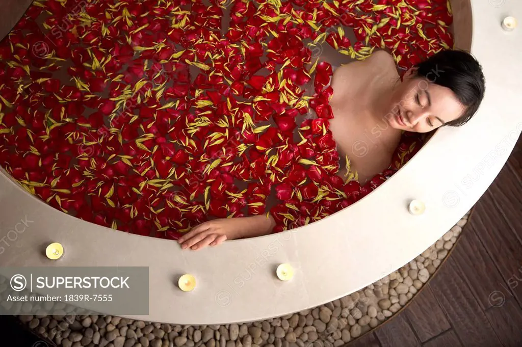 Woman relaxing in a rose petal bath
