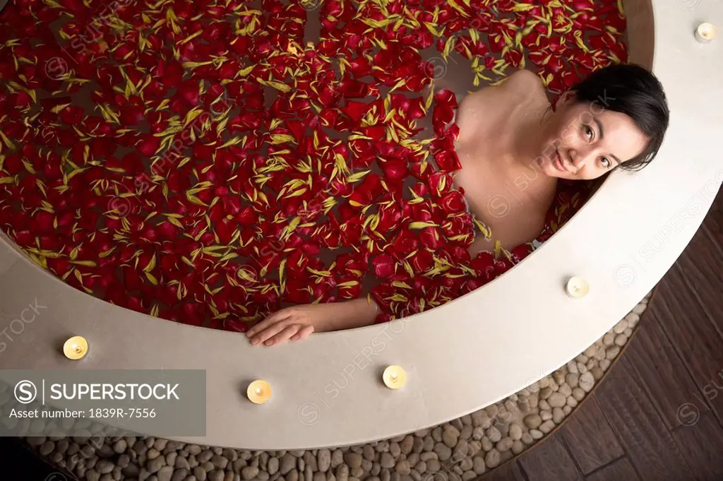 Woman relaxing in a rose petal bath