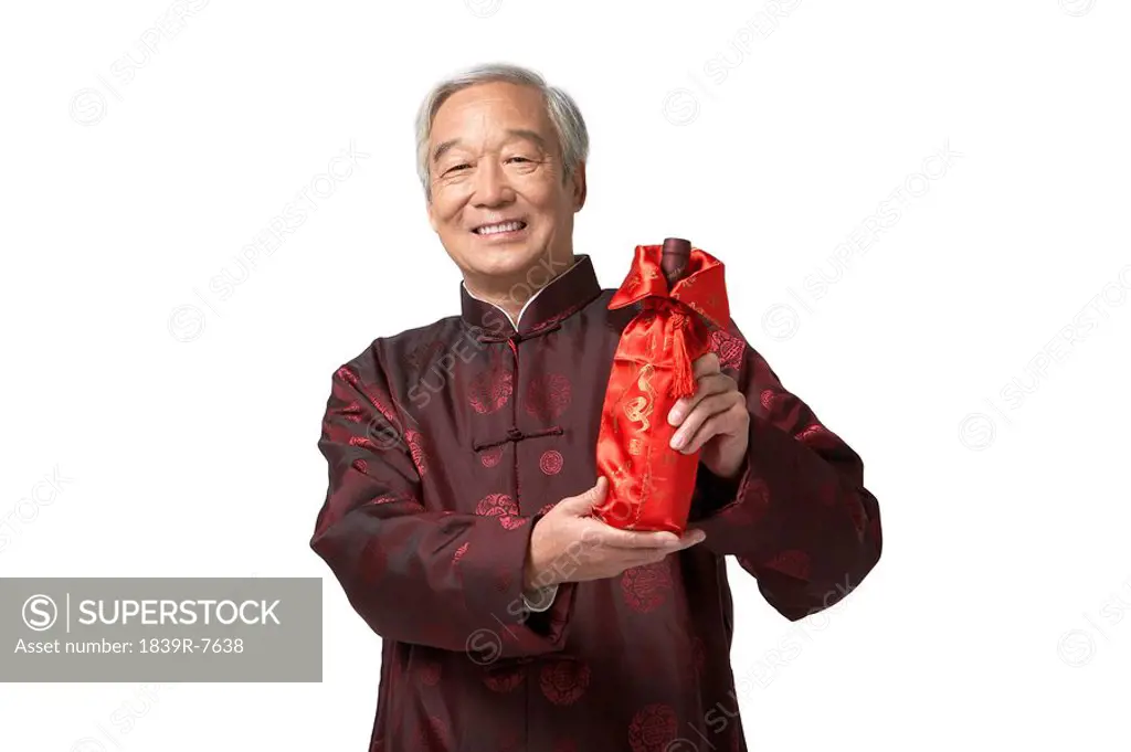 An elderly gentleman gifting a bottle of wine