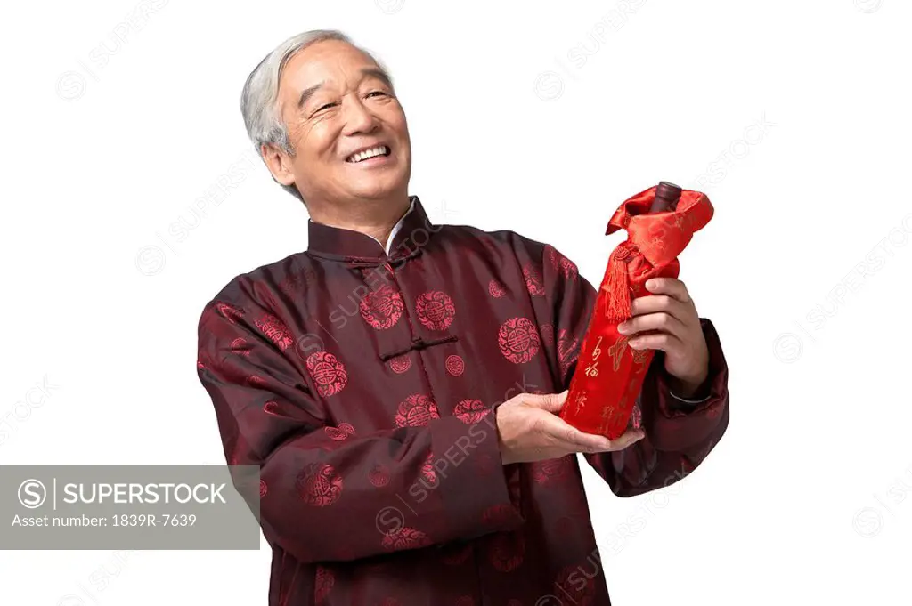 An elderly gentleman laughs upon receipt of a bottle of wine