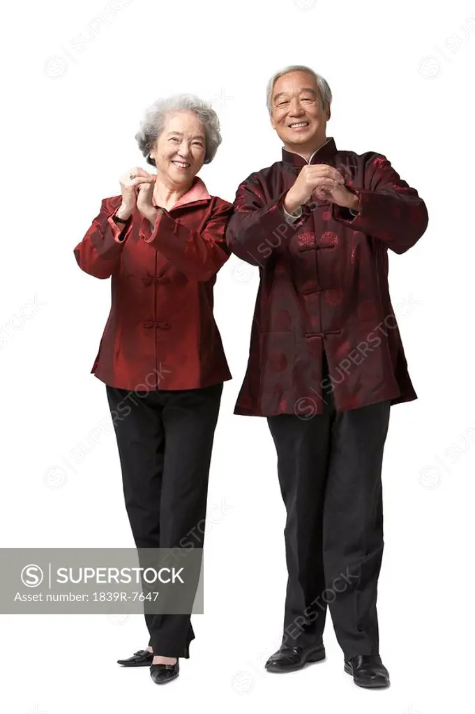 An elderly couple makes a gesture of greeting and good wishes